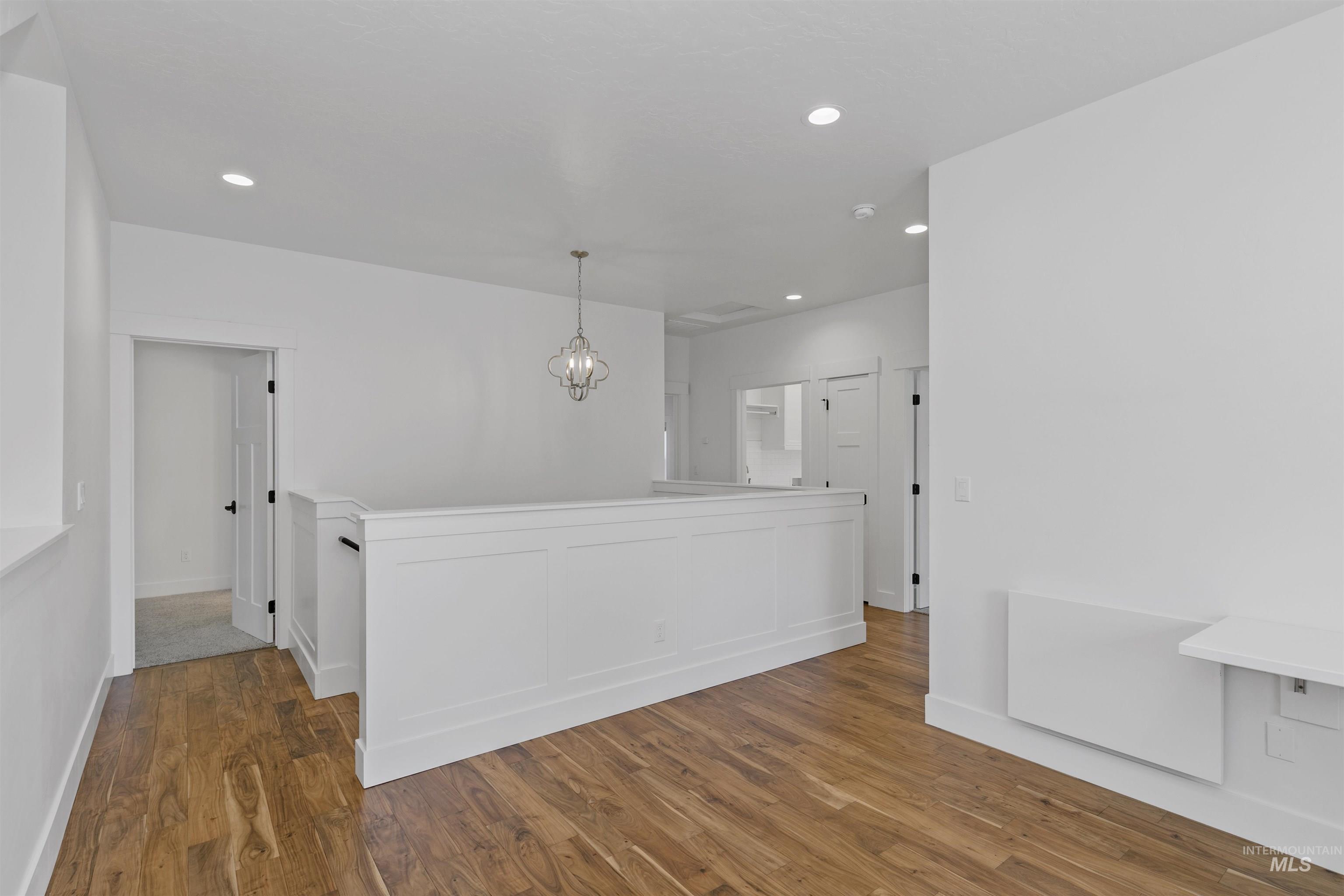 Unfurnished room with wood finished floors, recessed lighting, and a chandelier