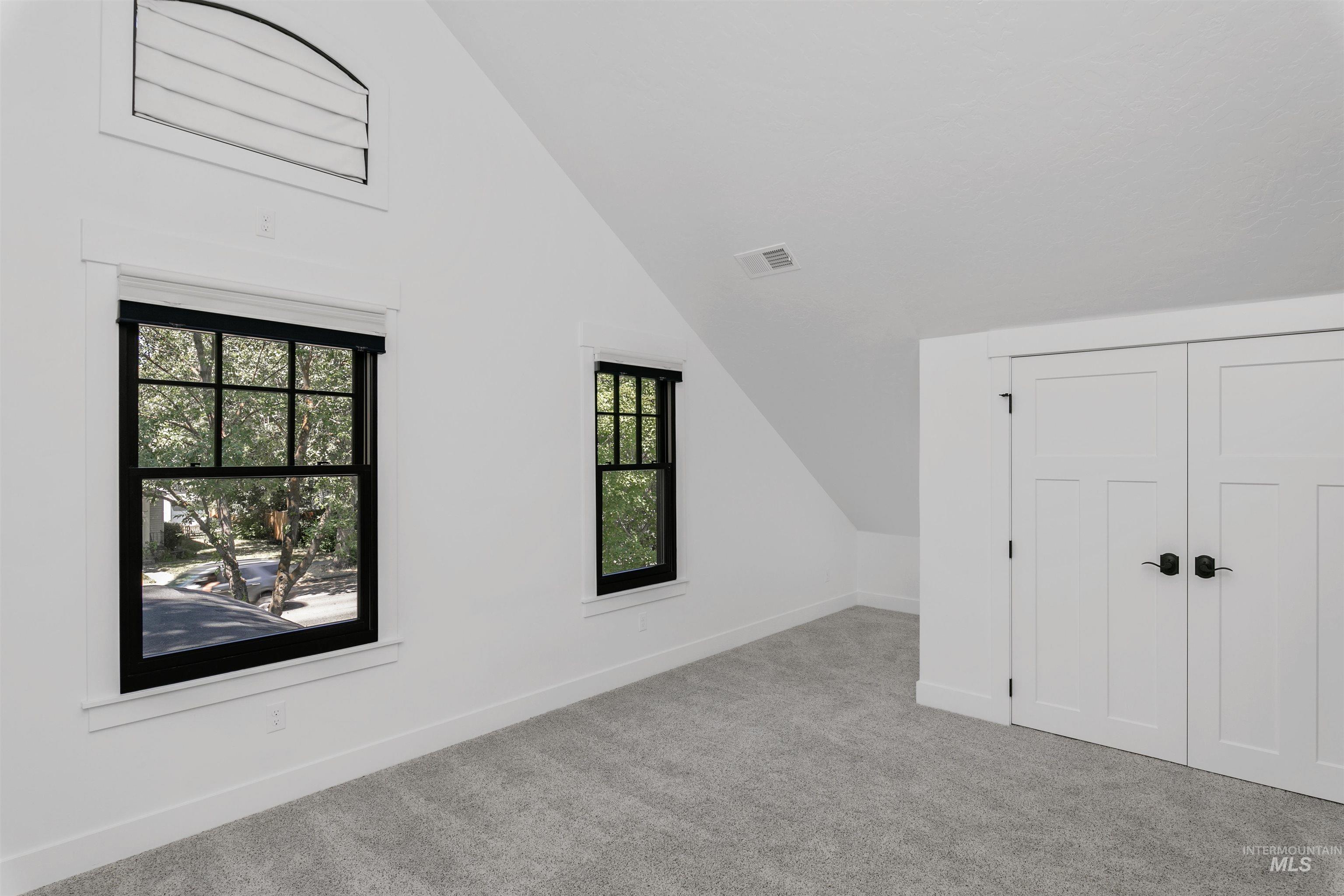 Additional living space with vaulted ceiling and carpet flooring