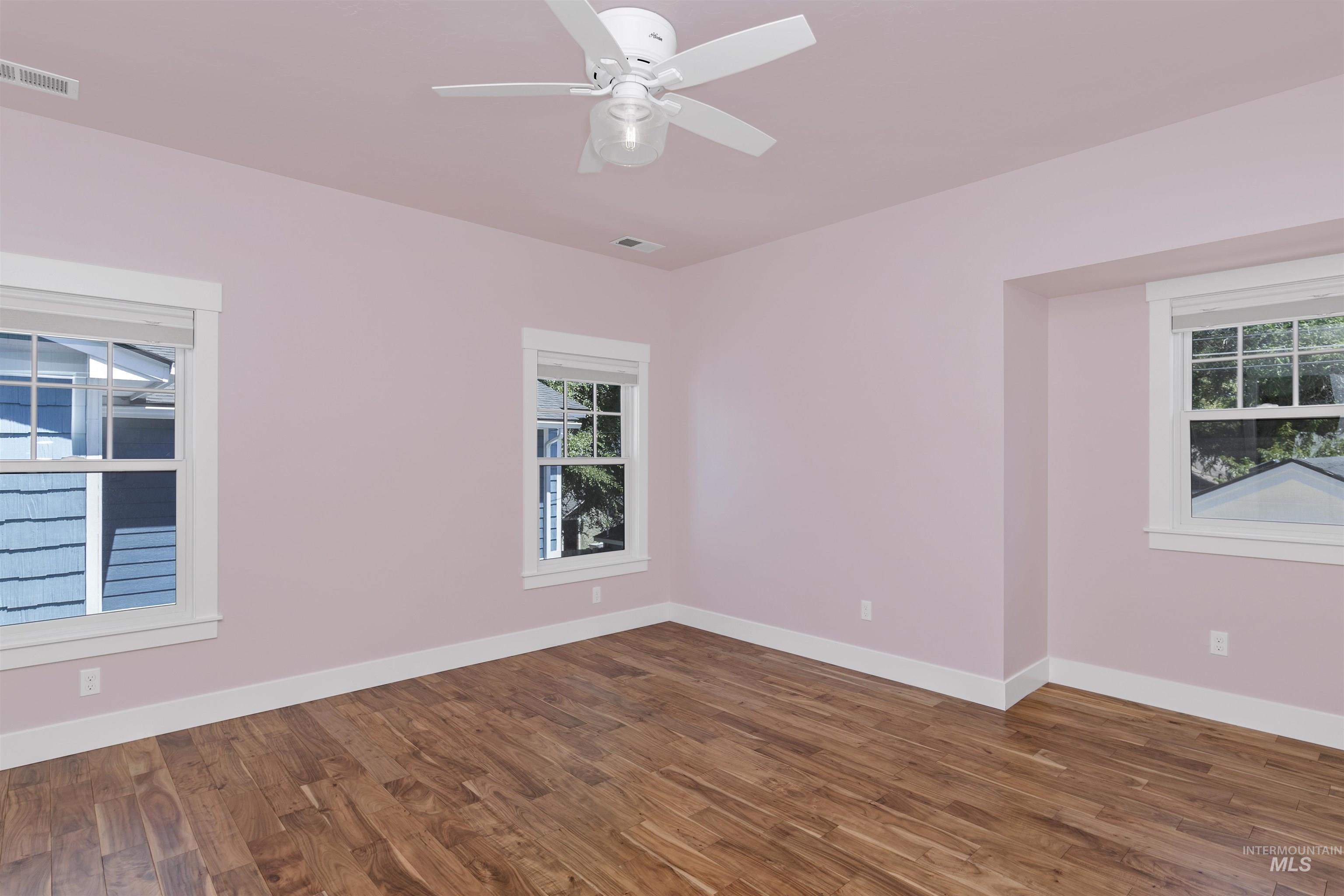 Spare room with dark wood finished floors, healthy amount of natural light, and a ceiling fan