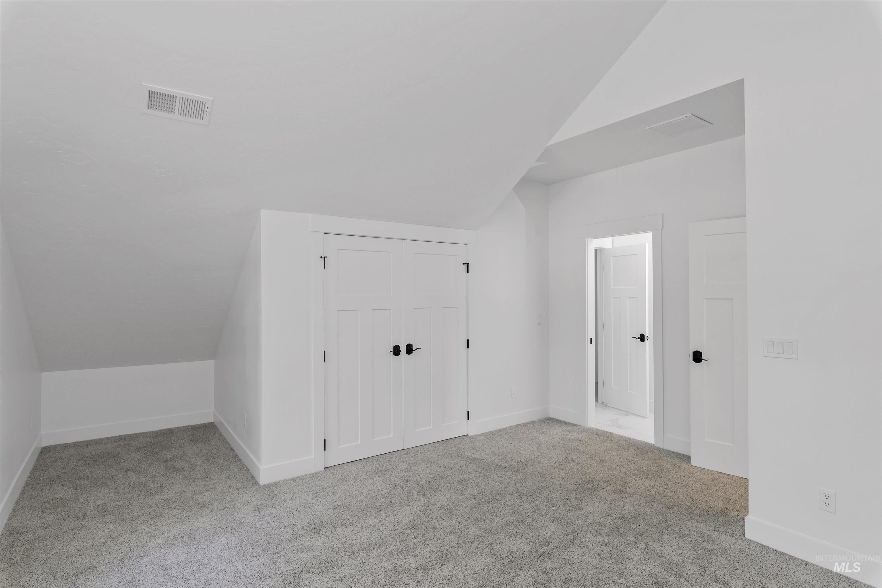 Additional living space featuring lofted ceiling and light colored carpet