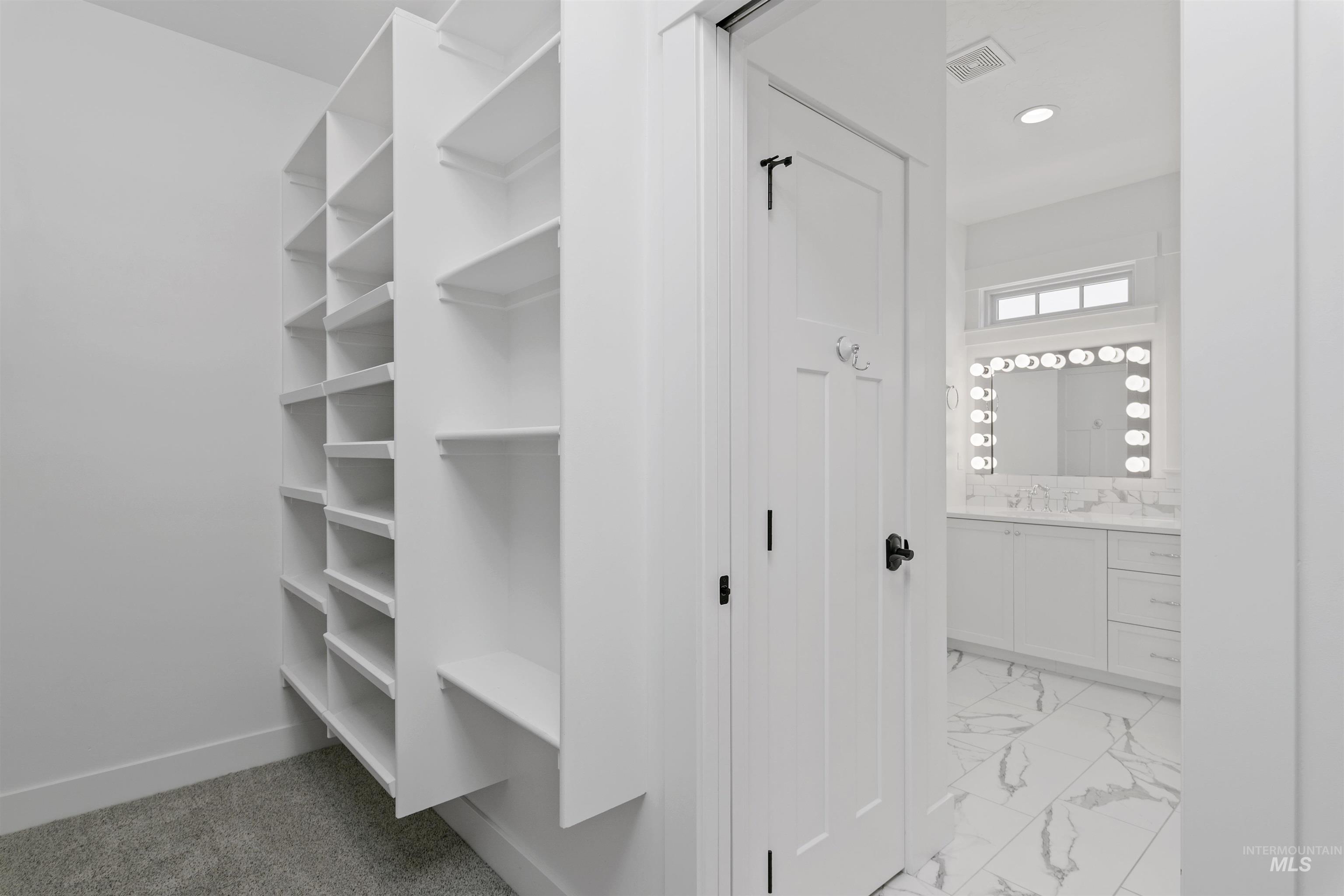 Walk in closet featuring light marble finish floors