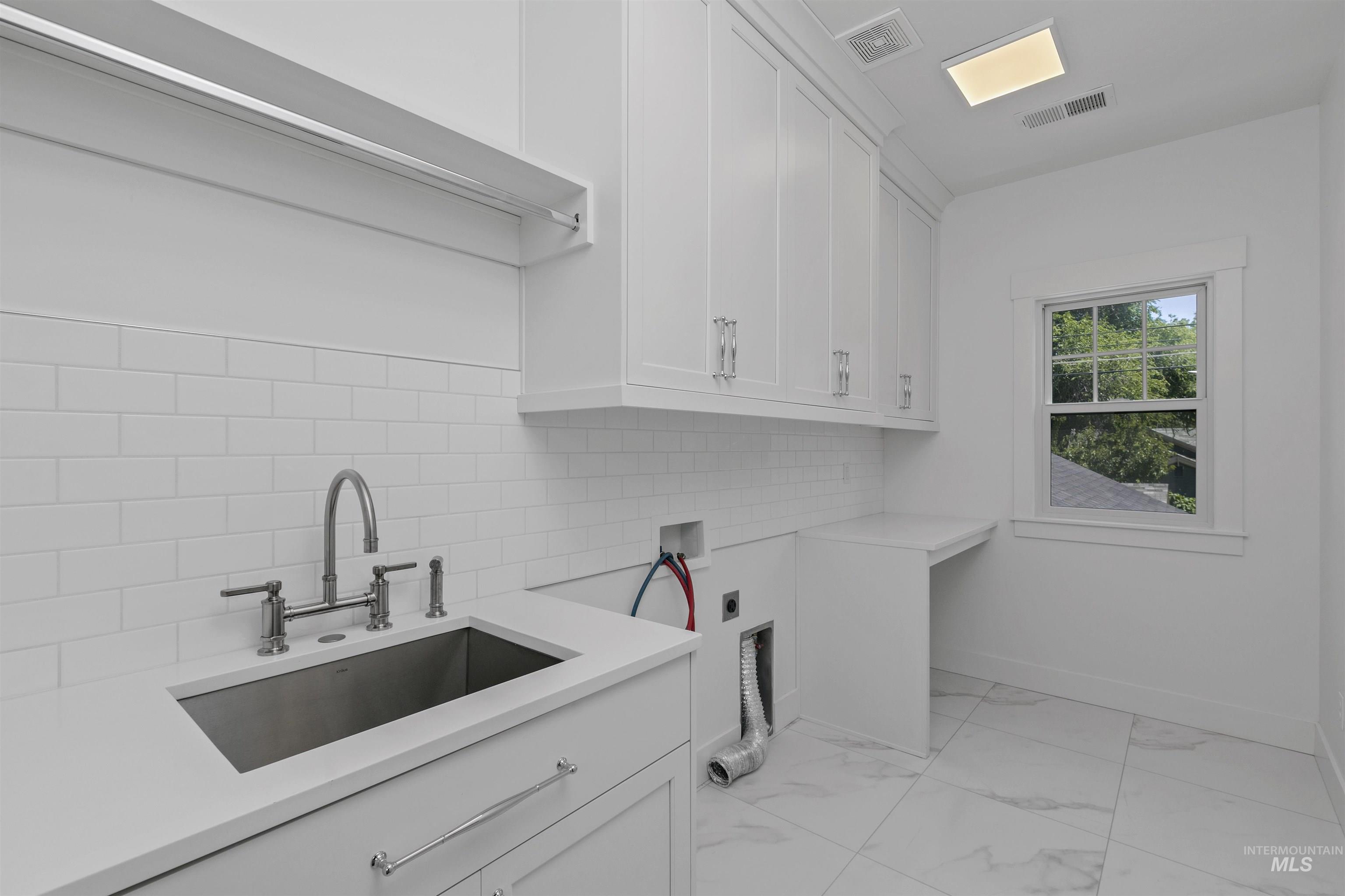 Laundry area featuring light marble finish flooring, hookup for a washing machine, hookup for an electric dryer, and cabinet space