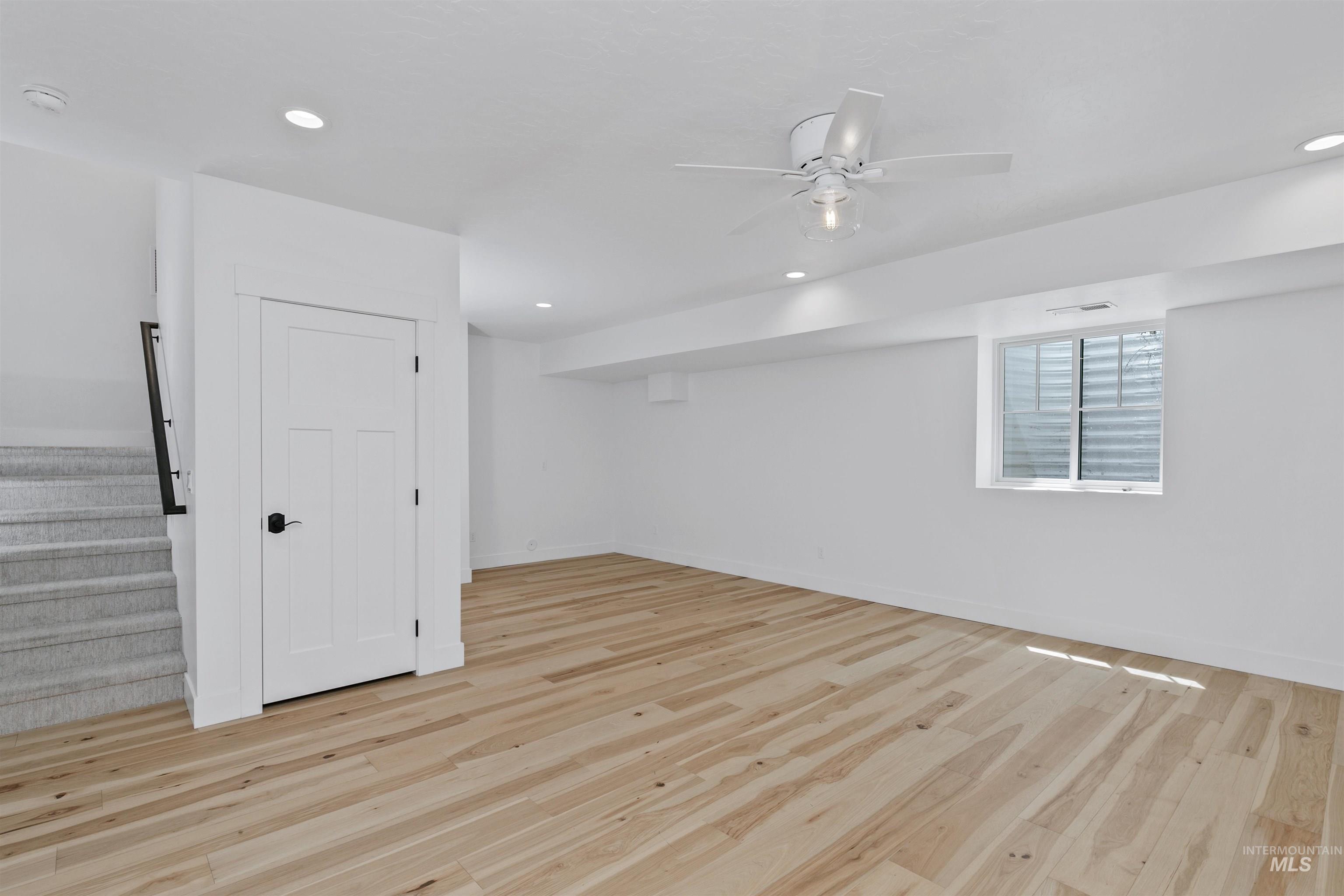 Below grade area featuring light wood-style floors, stairway, recessed lighting, and a ceiling fan