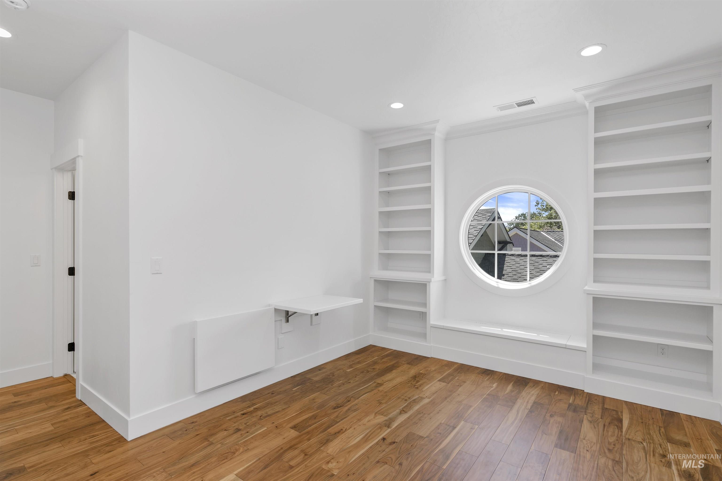 Unfurnished room with wood-type flooring, recessed lighting, and built in shelves