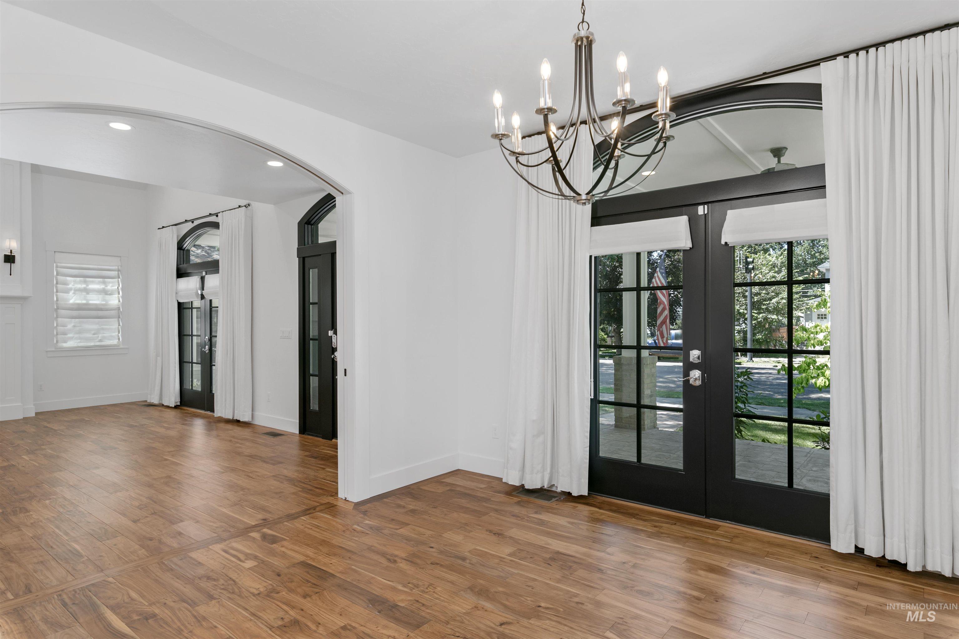 Unfurnished dining area featuring french doors, wood finished floors, plenty of natural light, recessed lighting, and a chandelier