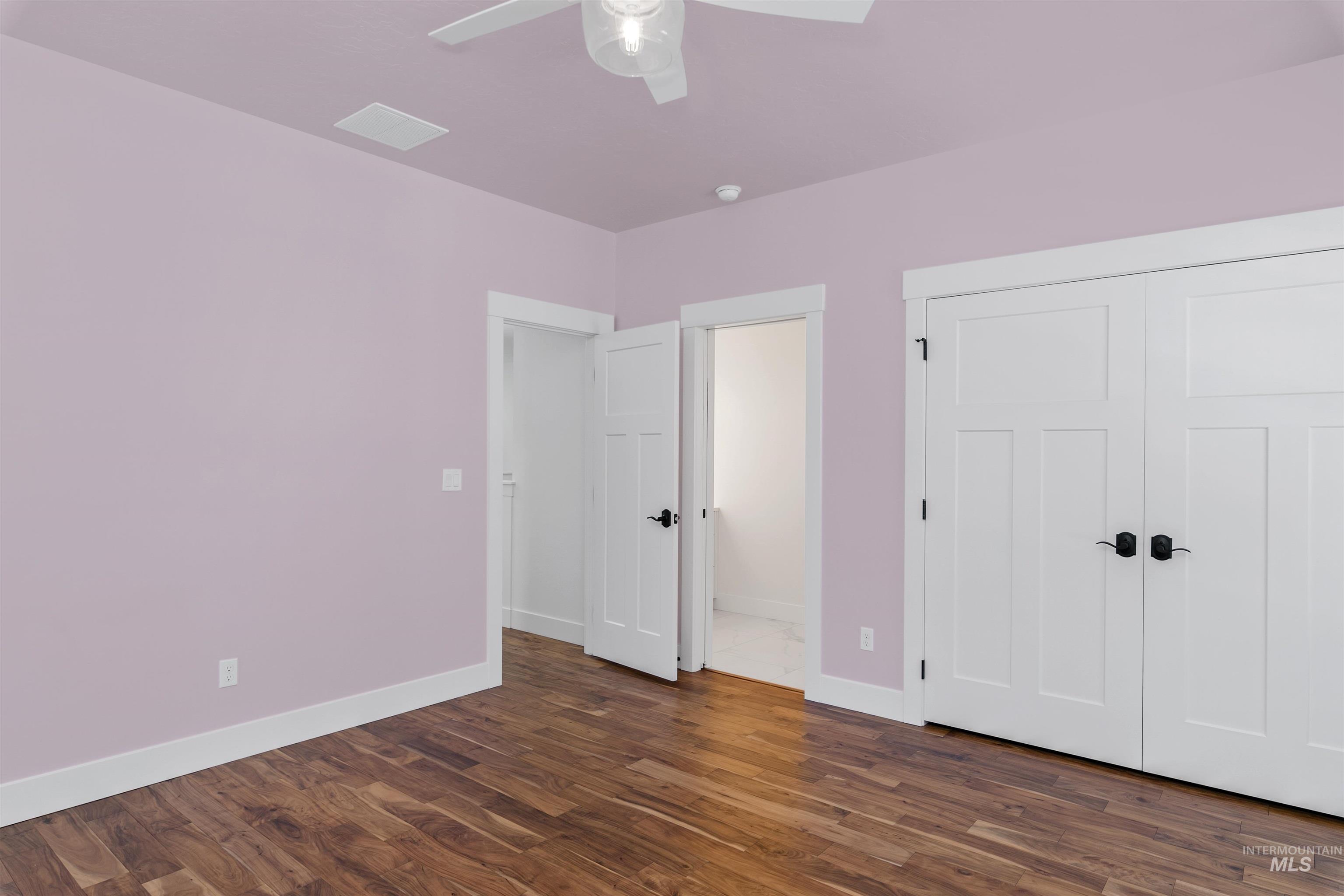 Unfurnished bedroom featuring dark wood-type flooring, a closet, and ceiling fan