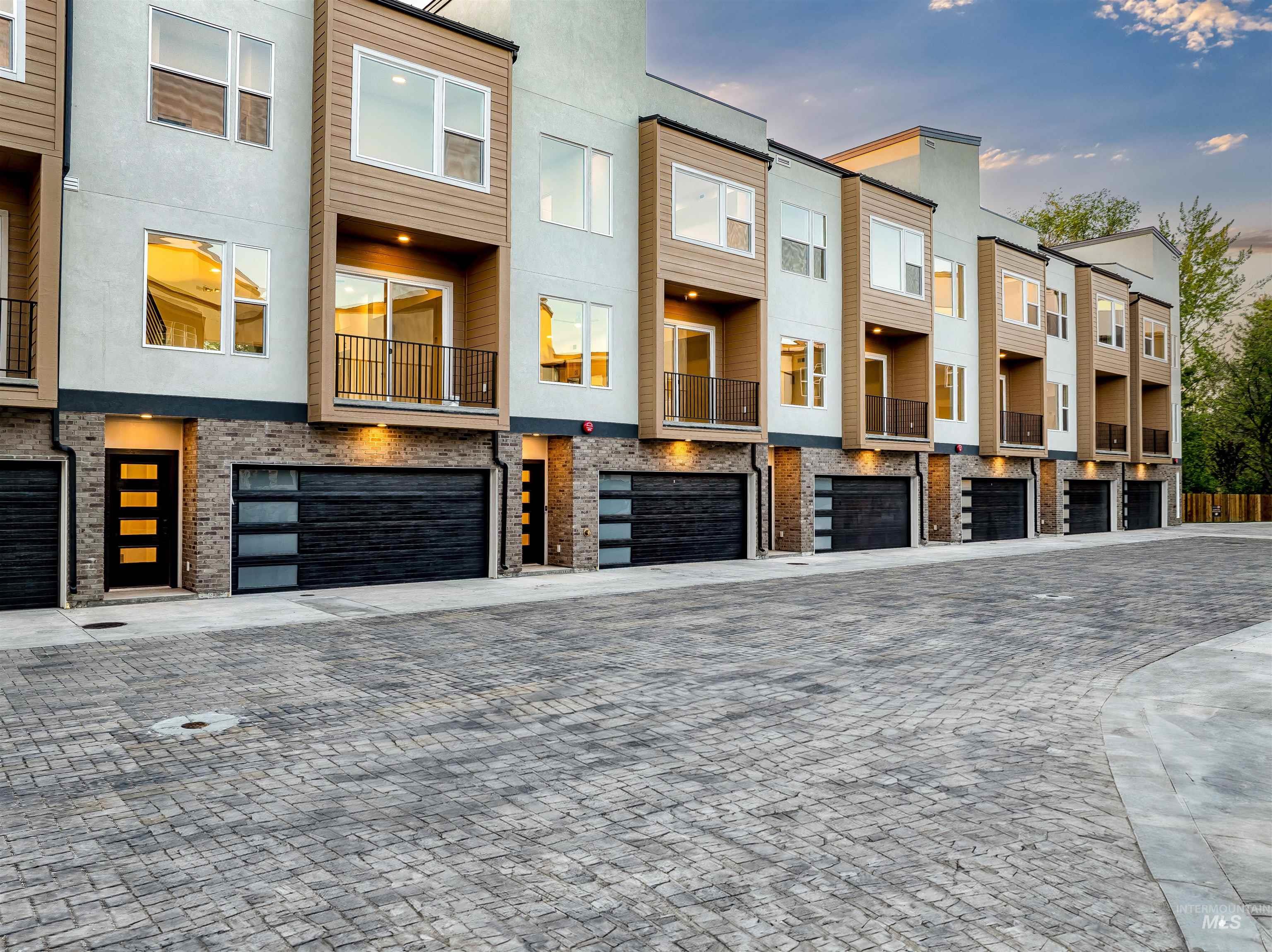View of front of home featuring stucco siding, a residential view, decorative driveway, and an attached garage