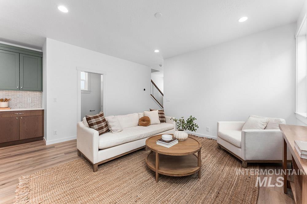 Living room featuring light wood-style flooring, stairway, and recessed lighting