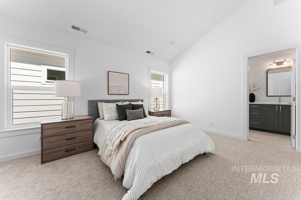 Bedroom featuring light carpet, high vaulted ceiling, and ensuite bathroom