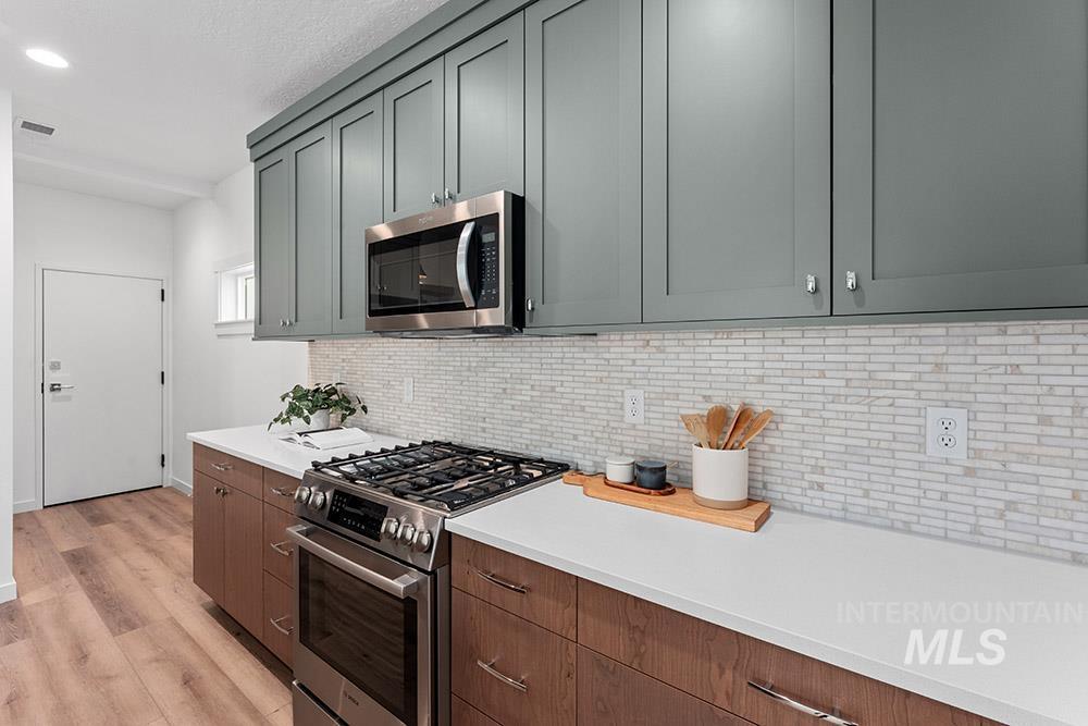 Kitchen with appliances with stainless steel finishes, light countertops, light wood-style flooring, tasteful backsplash, and a textured ceiling