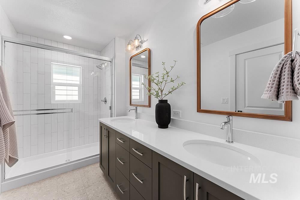 Full bathroom featuring double vanity and tiled shower