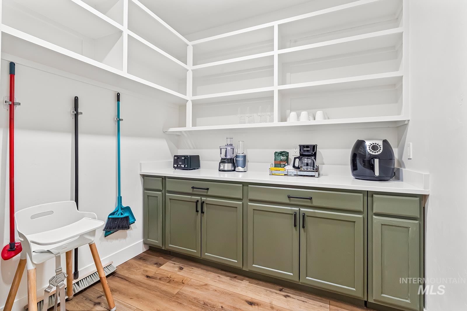 Bar area with light wood-style flooring, green cabinetry, a baseboard heating unit, and light stone countertops
