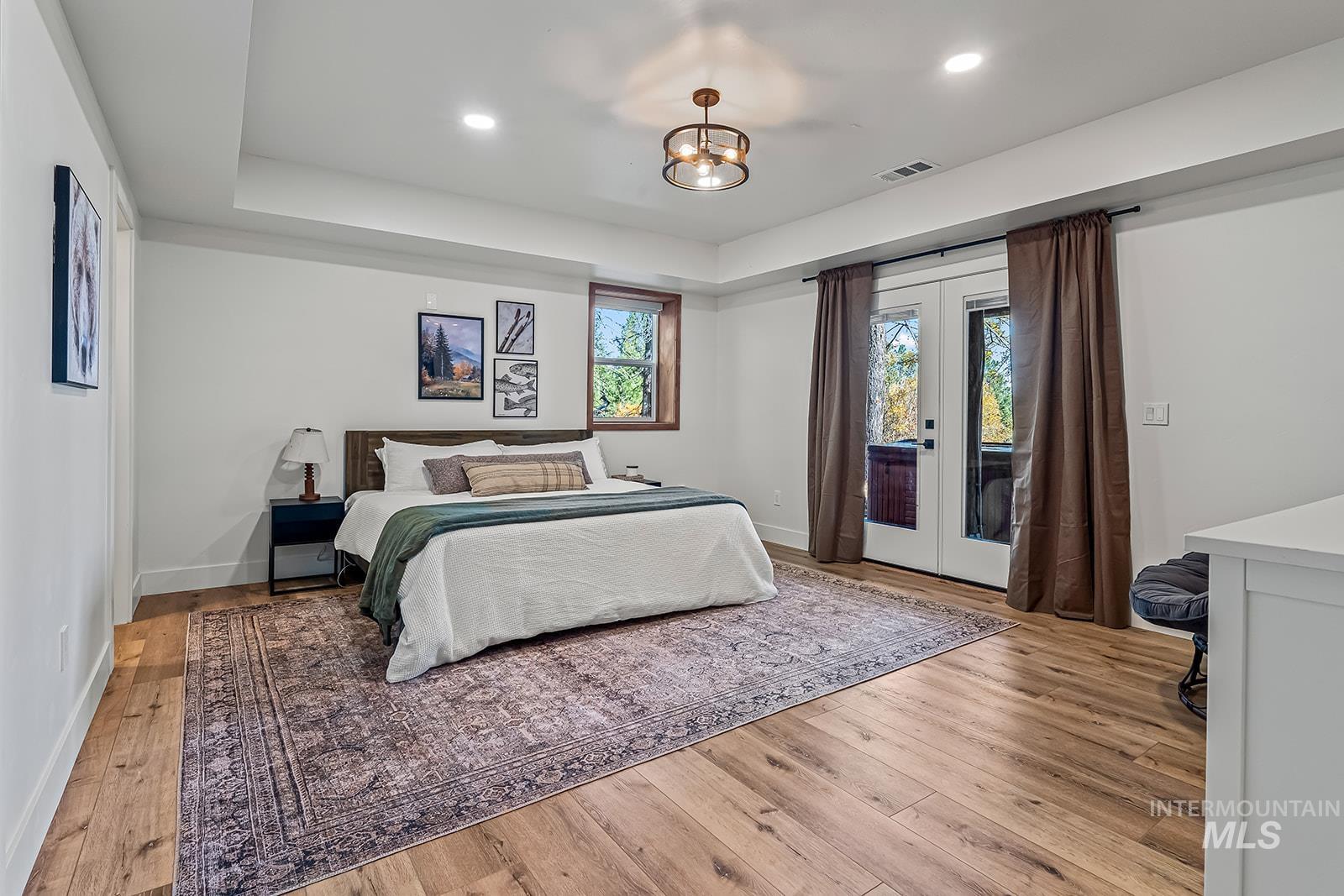Bedroom with french doors, access to outside, light wood-style flooring, and hanging lights
