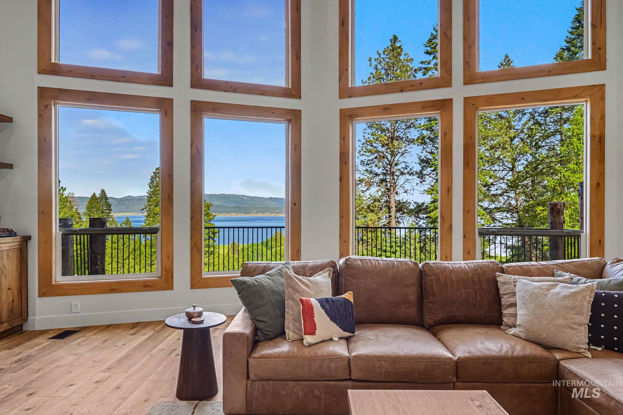 Double-height windows with natural wood trim framing expansive water and tree line scenery