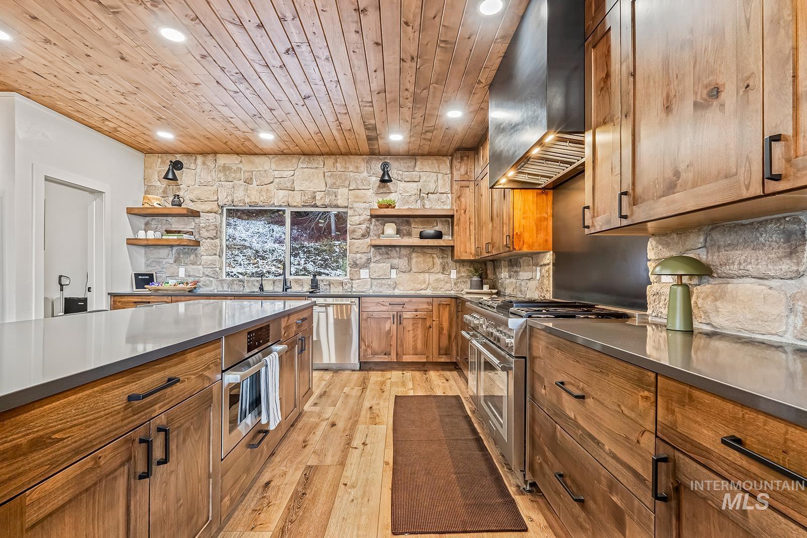 Kitchen with stainless steel countertops, stainless steel appliances, wood finish cabinets, light wood-style floors, and open shelves
