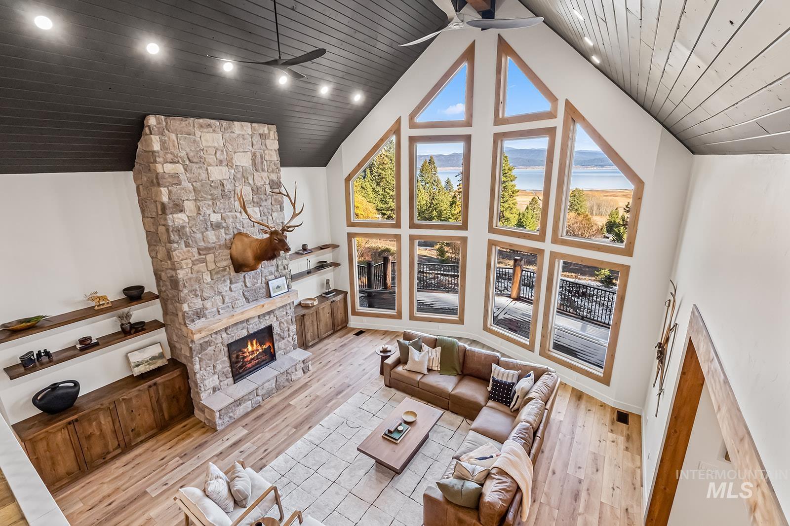 Living room featuring a ceiling fan, a high wood ceiling, light wood-style flooring, and a fireplace