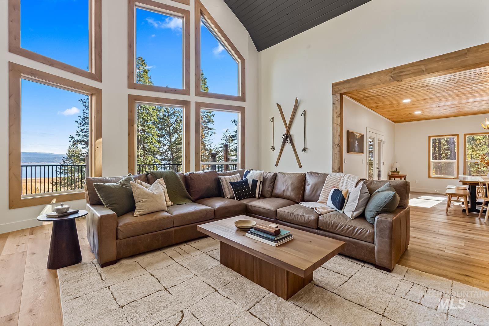 Living area with a high wooden ceiling, light wood-style flooring, and a water view