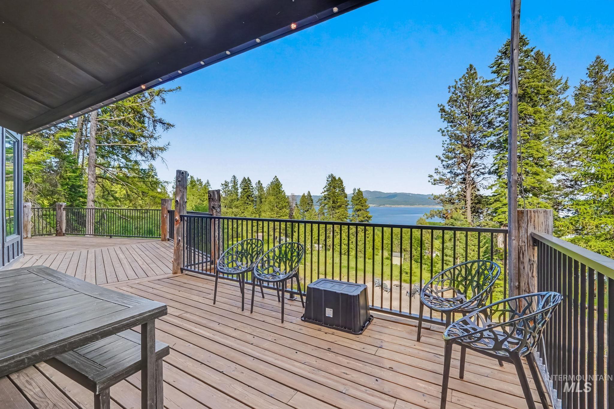 Expansive outdoor deck featuring wood-finish decking, a black metal railing, and a partial overhead awning