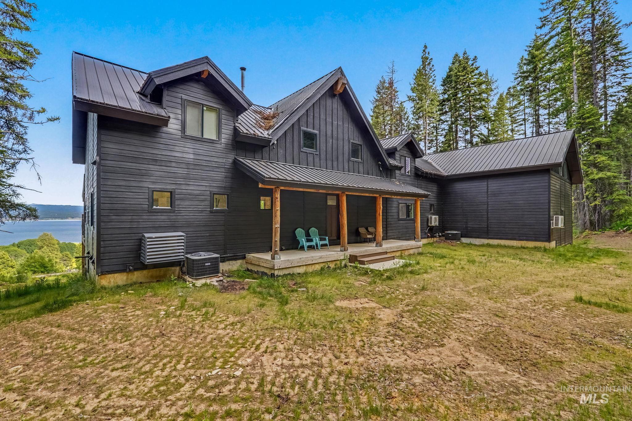 Modern black exterior with a metal roof and a covered front porch featuring natural wood pillars