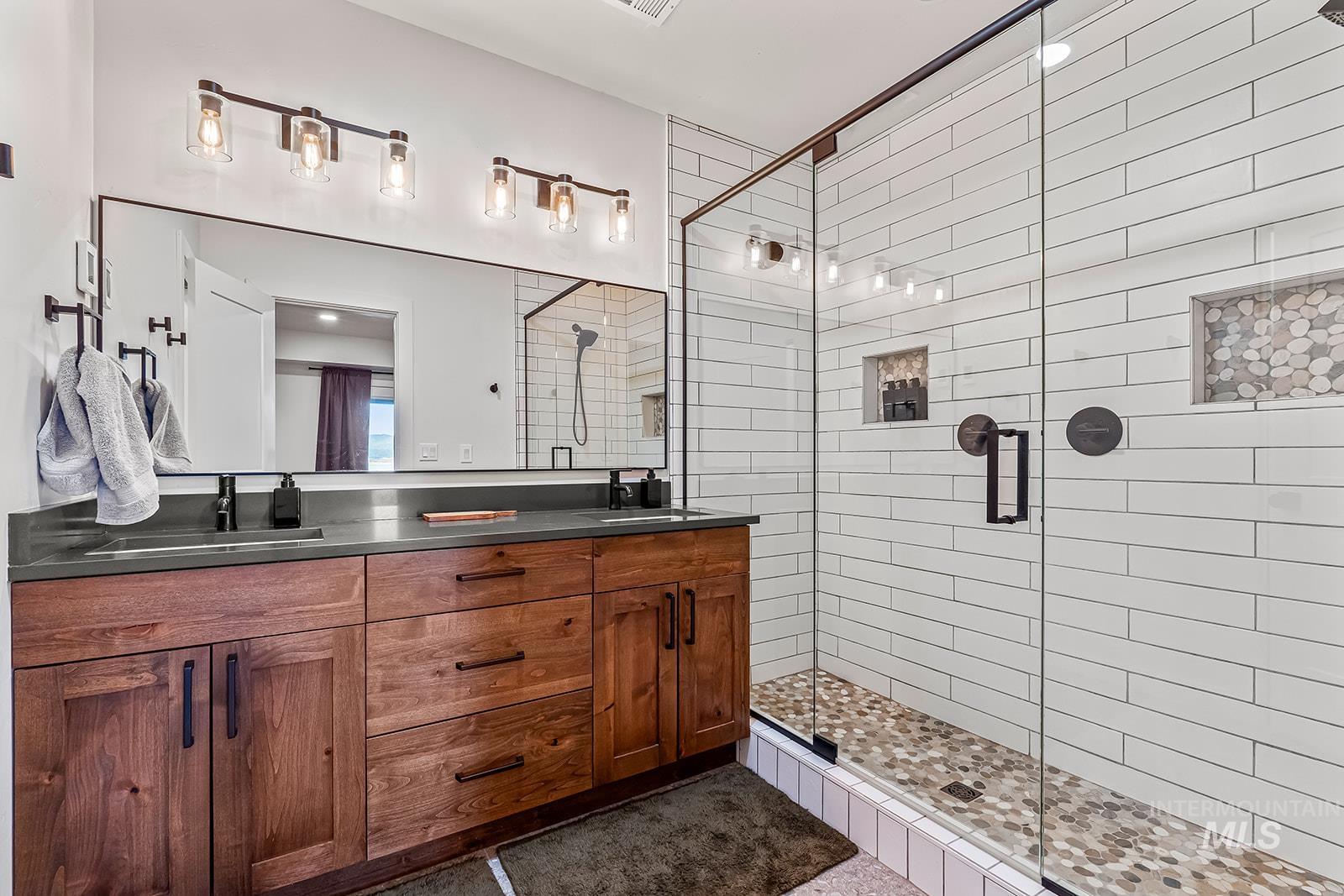 Bathroom featuring double vanity and a shower stall