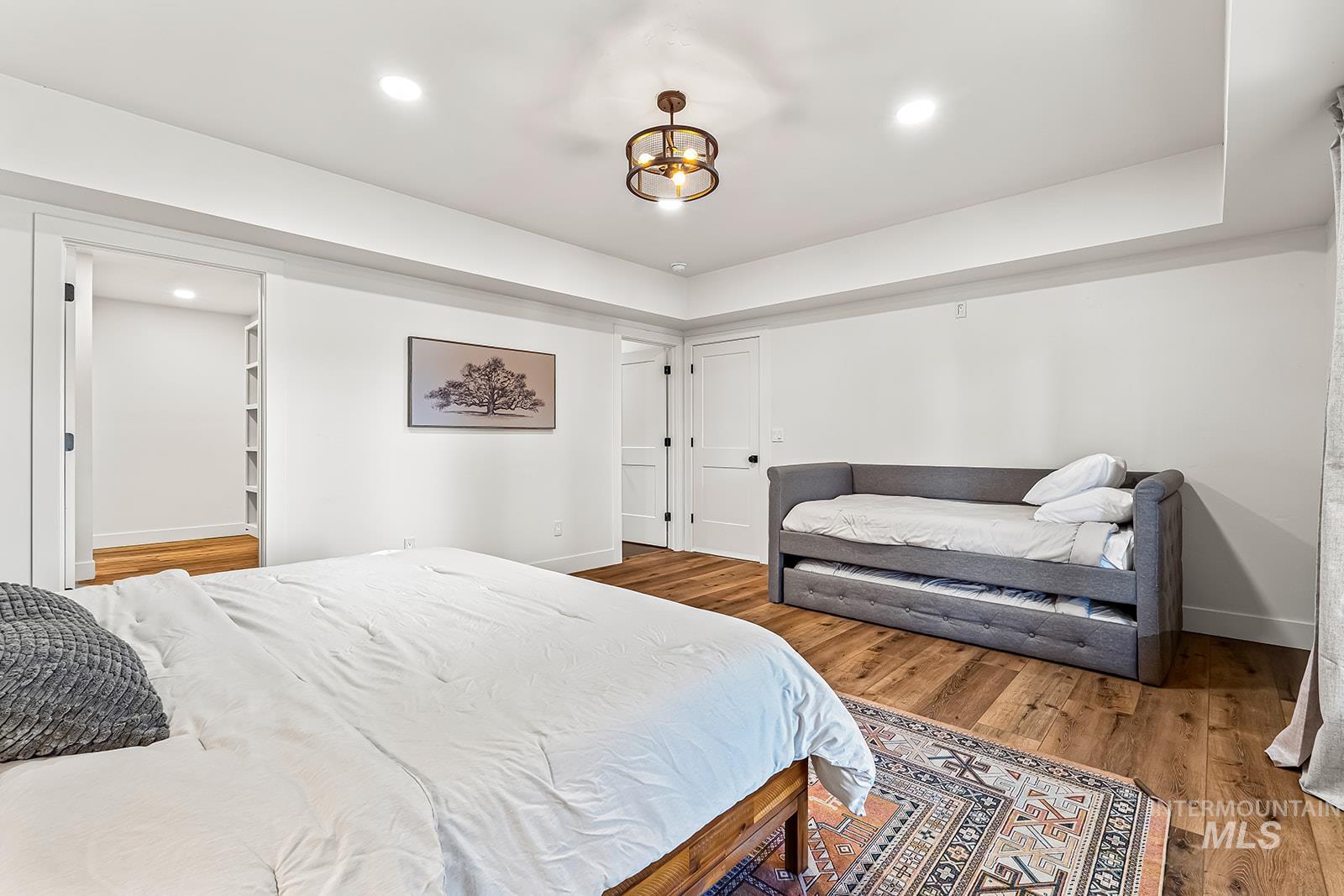 Bedroom featuring light wood finished floors, a tray ceiling, and recessed lighting