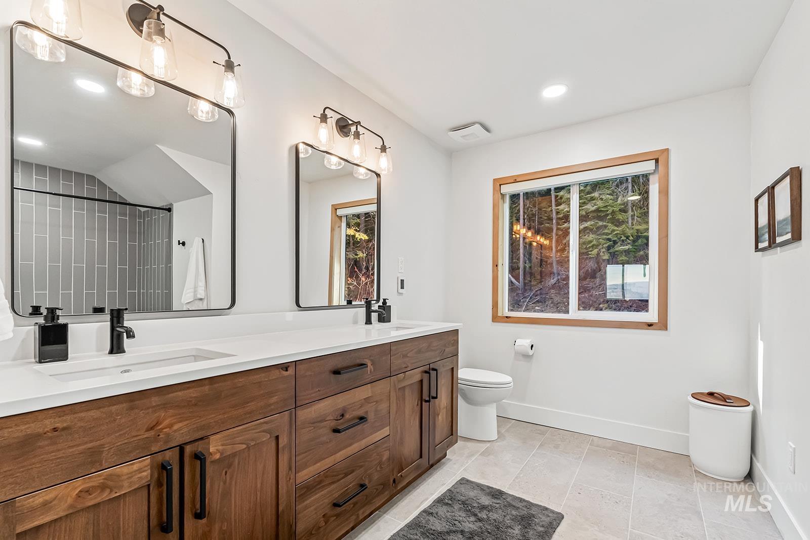 Full bathroom featuring double vanity, recessed lighting, a shower, plenty of natural light, and light tile patterned floors