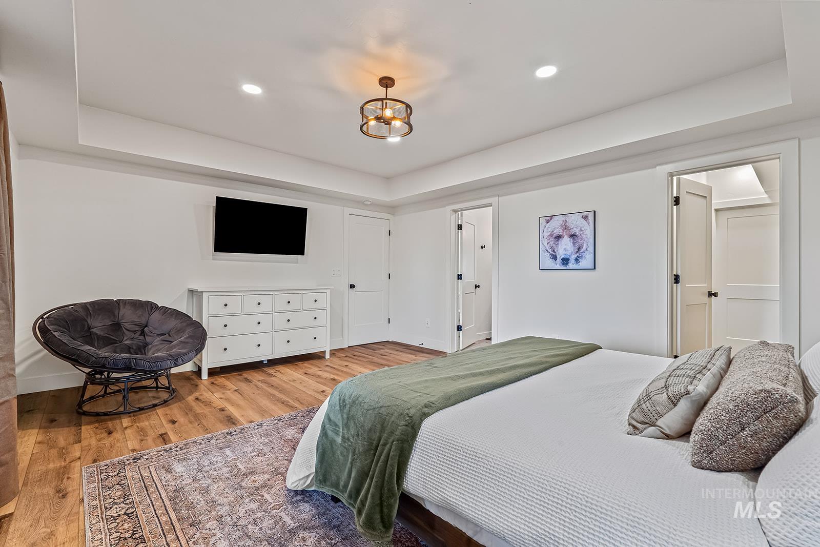 Bedroom featuring a tray ceiling, light wood-type flooring, and recessed lighting