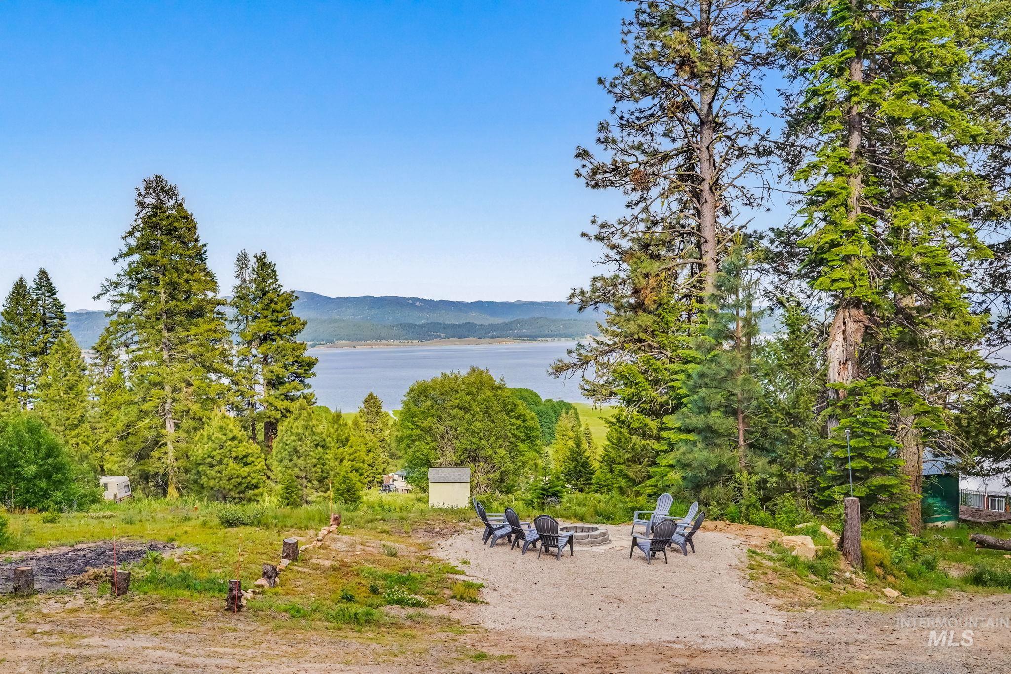 Outdoor fire pit area with seating, surrounded by mature trees