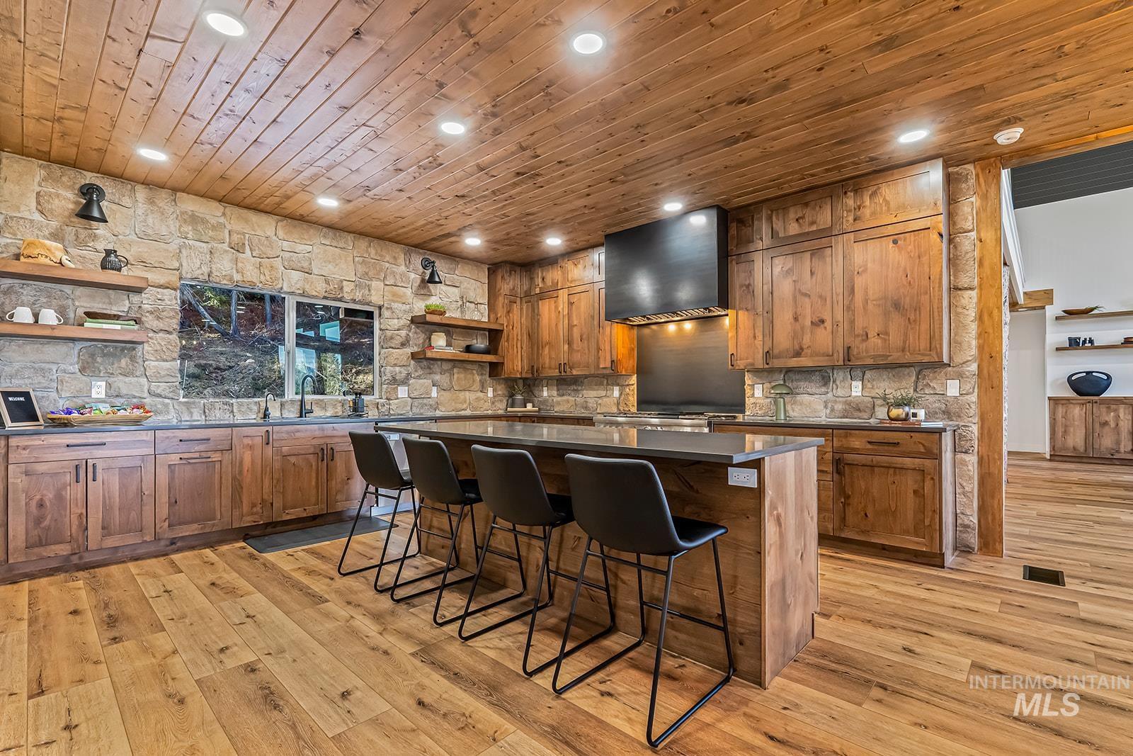 Kitchen with open shelves, wood finish cabinetry, a kitchen bar, wooden ceiling, and recessed lighting