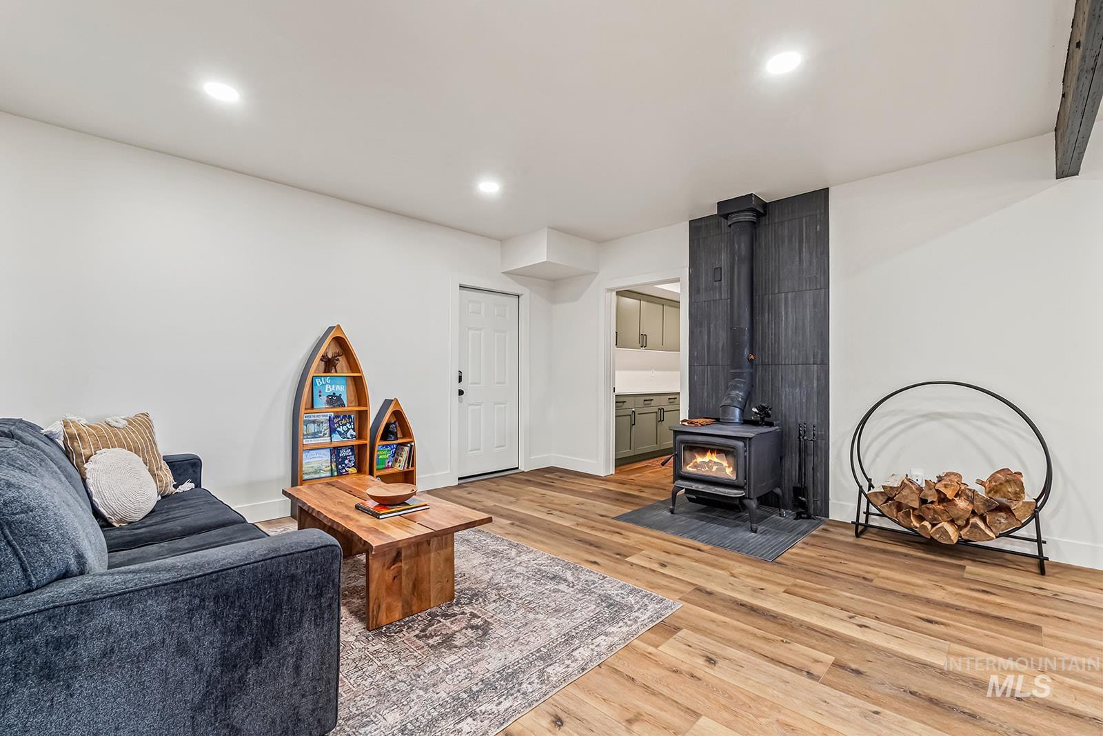 Living area featuring light wood-style flooring, a wood stove, and recessed lighting