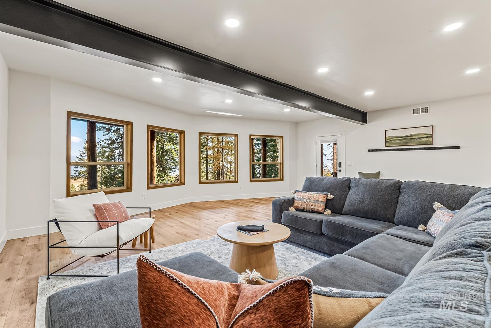Living area with beam ceiling, light wood-style flooring, healthy amount of natural light, and recessed lighting