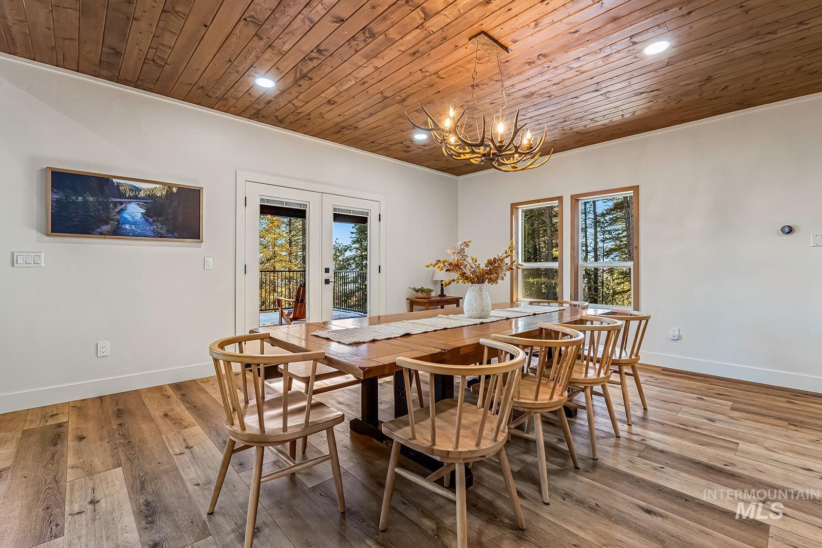 Dining room with light wood finished floors, suspended lighting, french doors, and wood ceiling