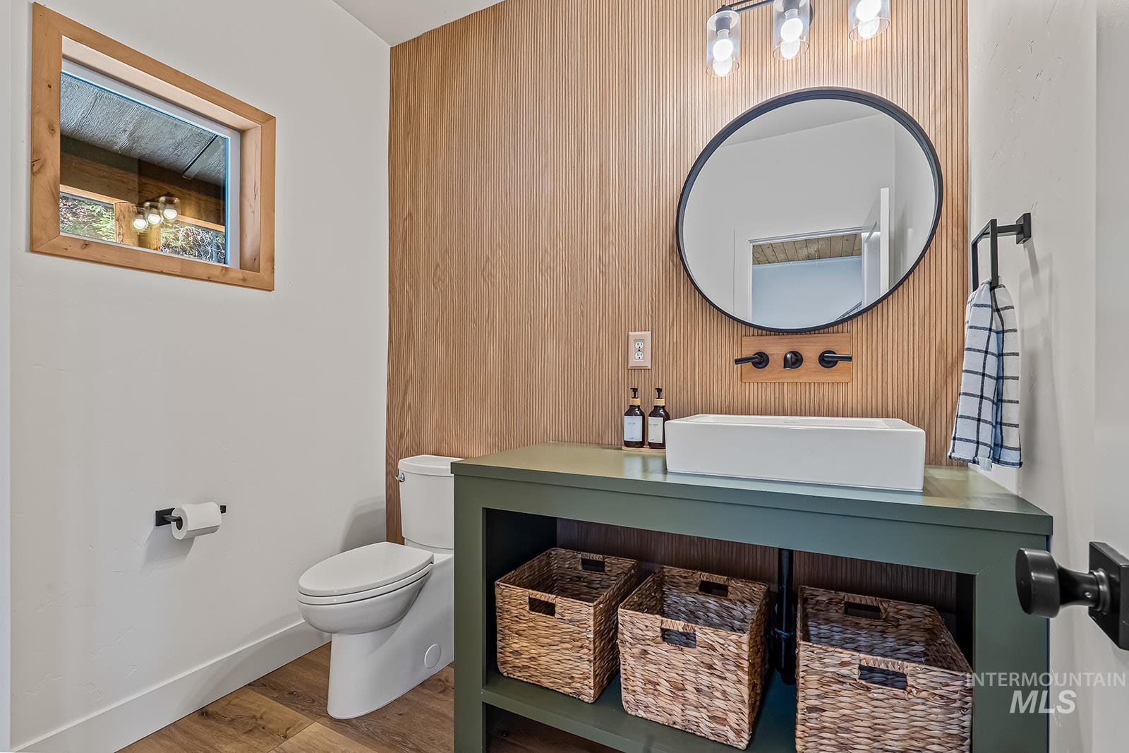 Half bath featuring wood finished floors, vanity, and wood walls