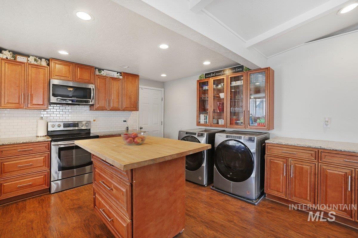 Kitchen featuring separate washer and dryer, stainless steel appliances, dark wood-type flooring, recessed lighting, and a center island