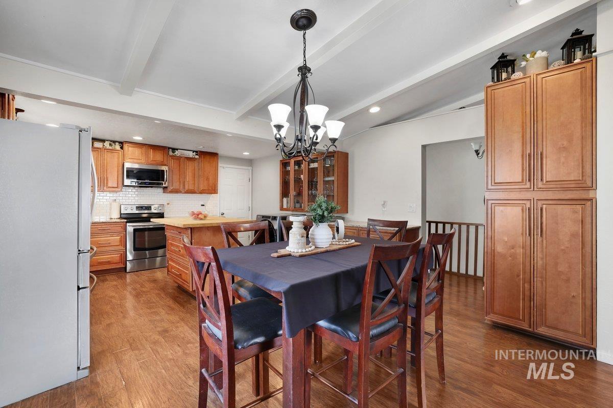 Dining space with a chandelier, beam ceiling, wood finished floors, and recessed lighting