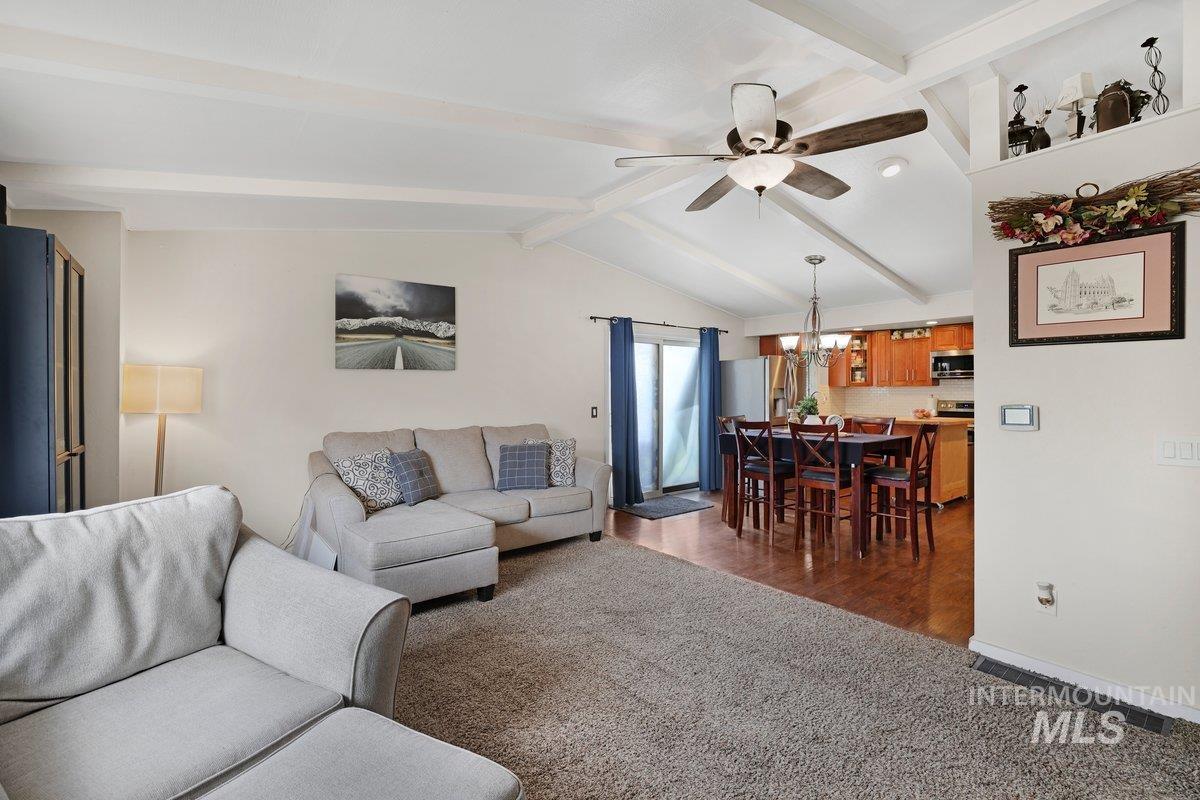 Living room with dark carpet, a ceiling fan, and a chandelier