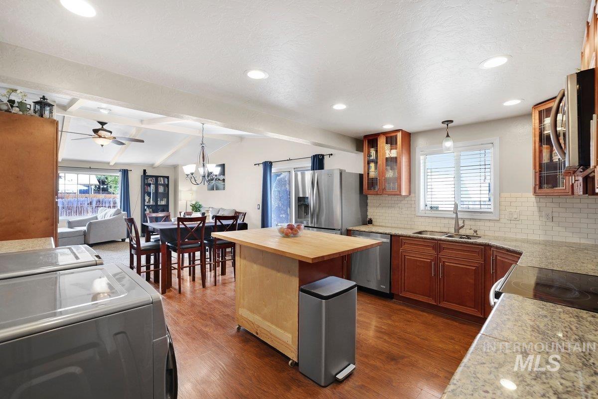 Kitchen featuring washer and clothes dryer, tasteful backsplash, ceiling fan, appliances with stainless steel finishes, and a chandelier