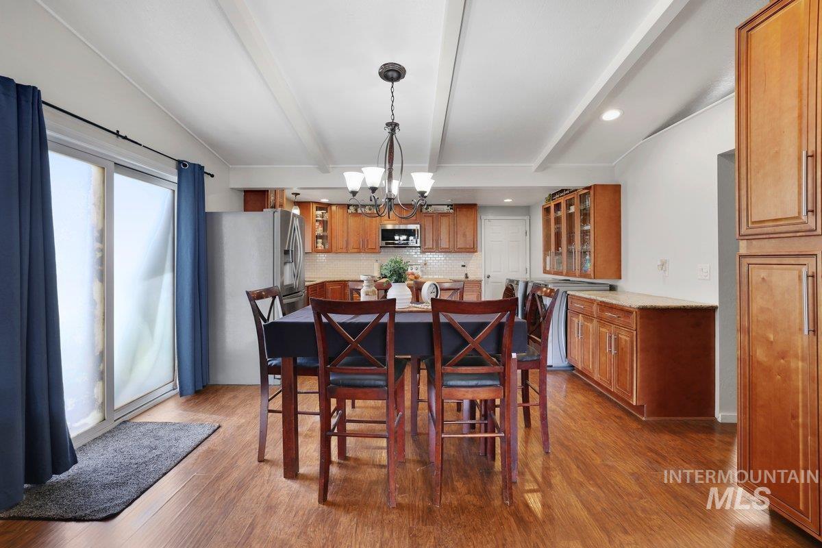 Dining room featuring a chandelier, beam ceiling, wood finished floors, and recessed lighting