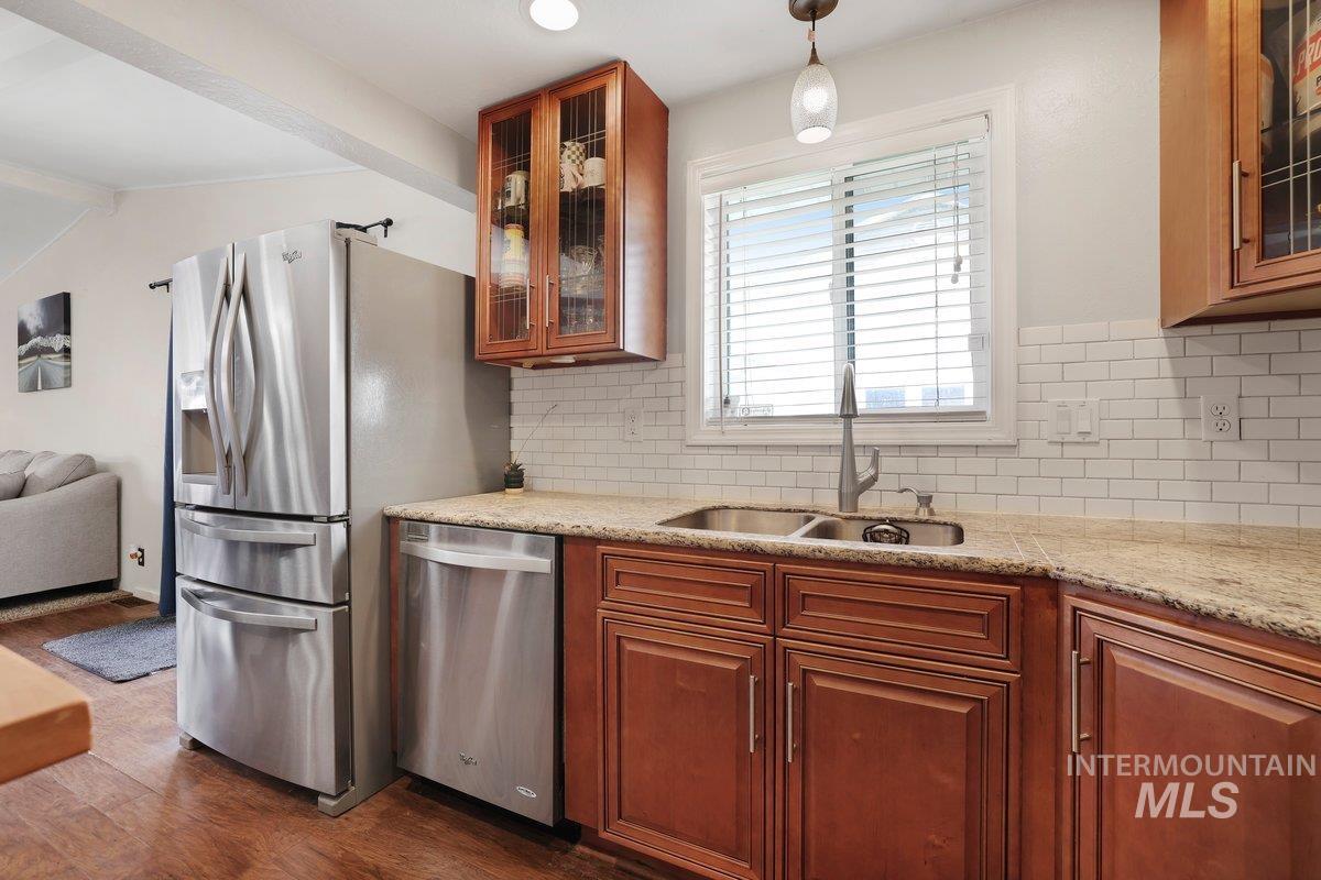 Kitchen with appliances with stainless steel finishes, backsplash, dark wood-style flooring, and glass insert cabinets