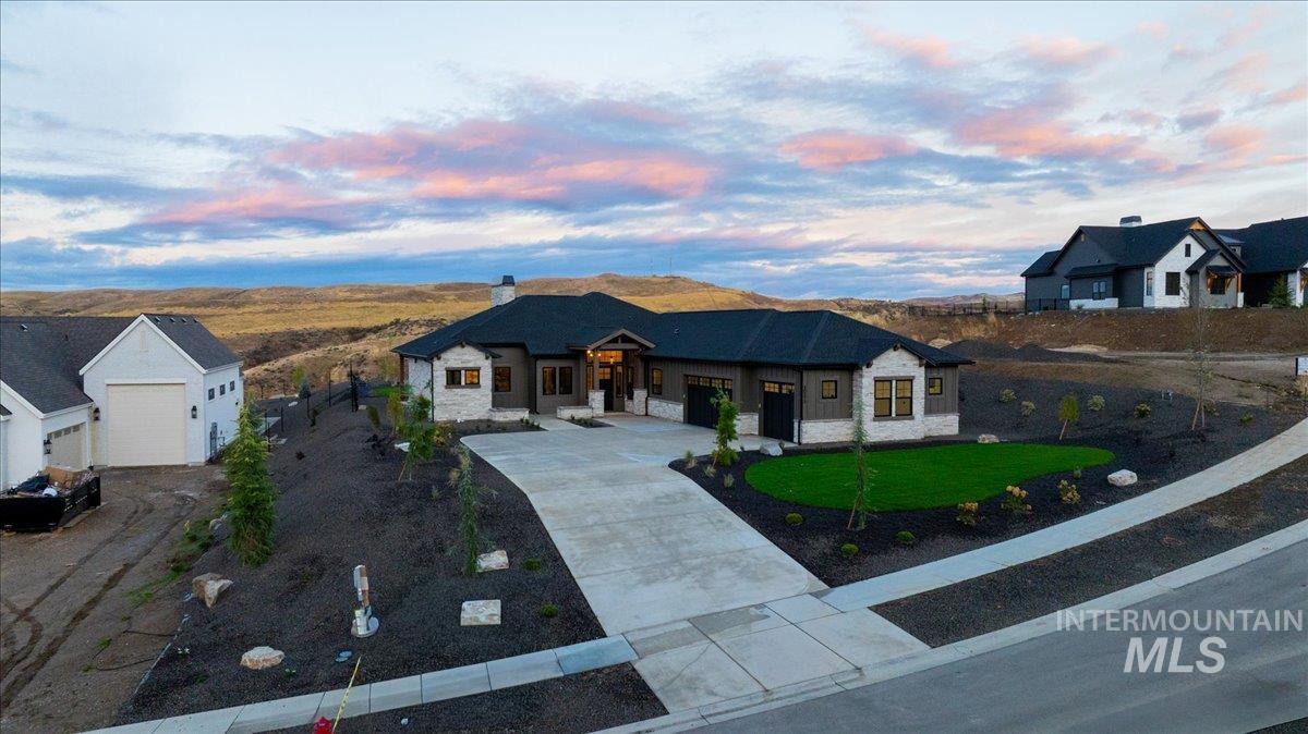 French country home with a chimney, concrete driveway, a yard, stone siding, and a garage