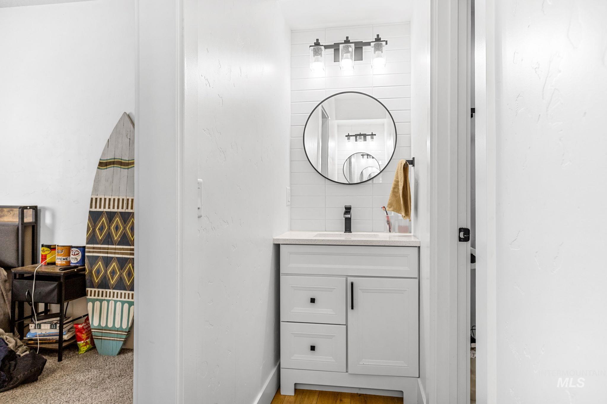 Vanity area featuring a white cabinet with dark hardware, a surface-mounted sink, and a black faucet