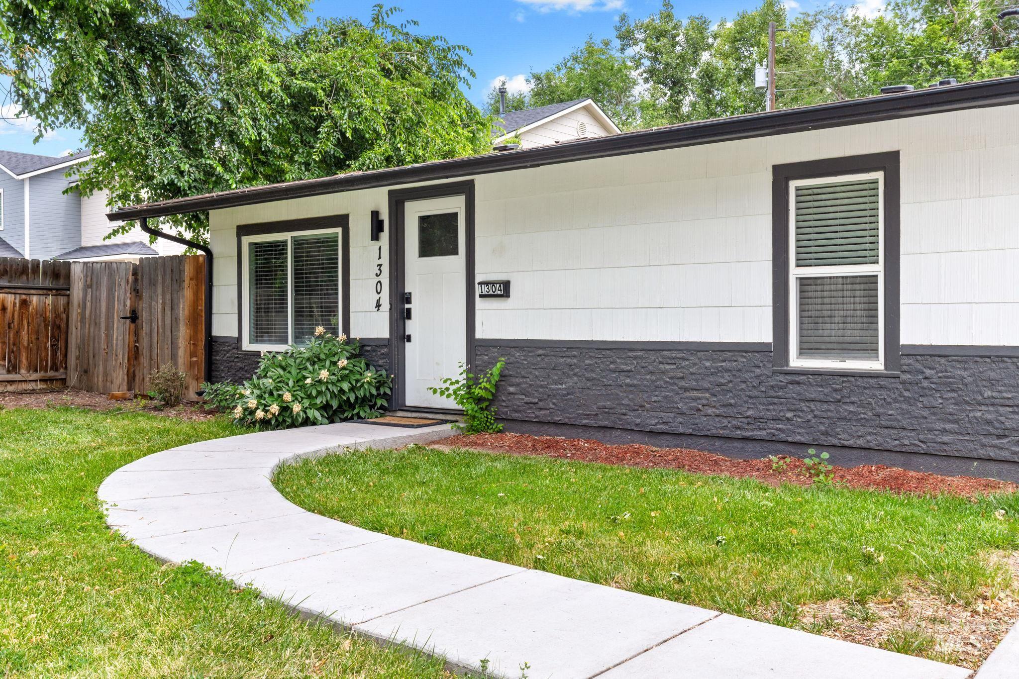 Contemporary single-story exterior featuring white horizontal siding and a dark gray stacked stone foundation