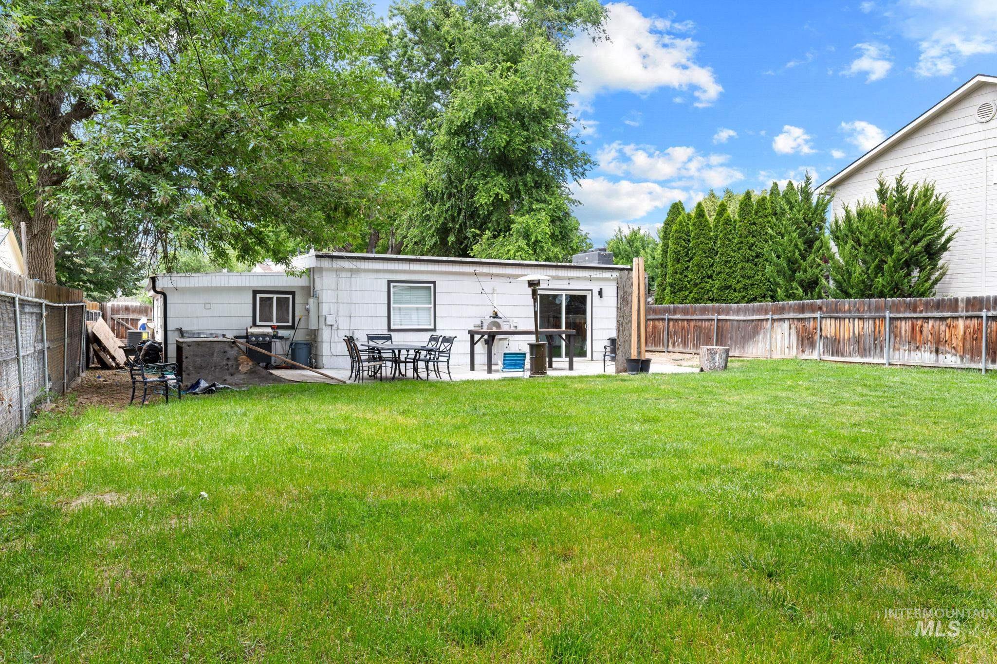 Expansive backyard featuring a manicured lawn, a concrete patio, and a privacy fence