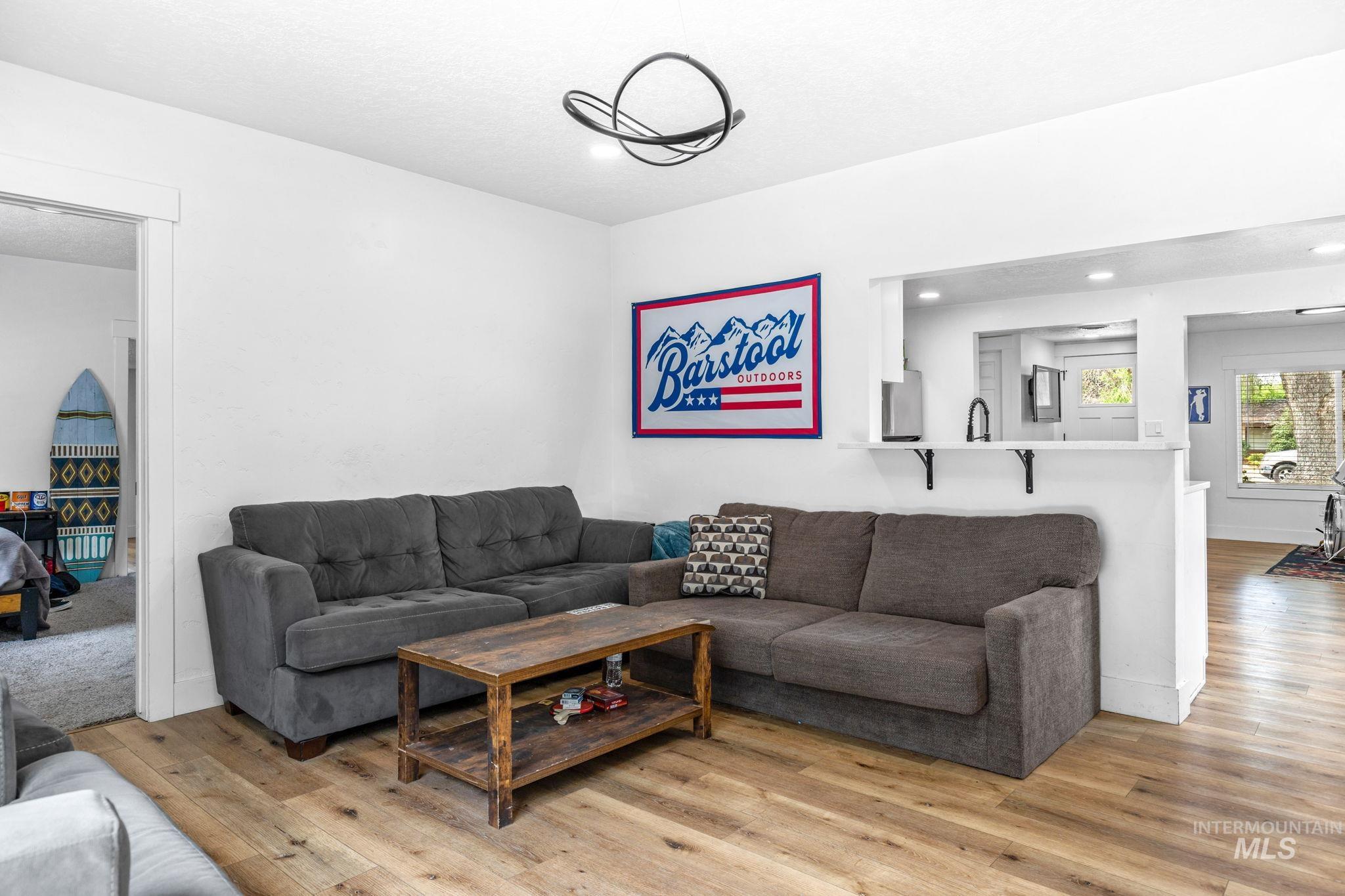 Open-concept living space featuring wood-finish flooring, white walls, and a contemporary ceiling light fixture