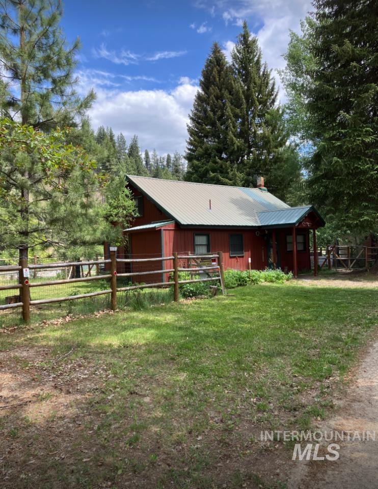 Chalet / cabin featuring an outdoor structure, a metal roof, an exterior structure, and view of scattered trees