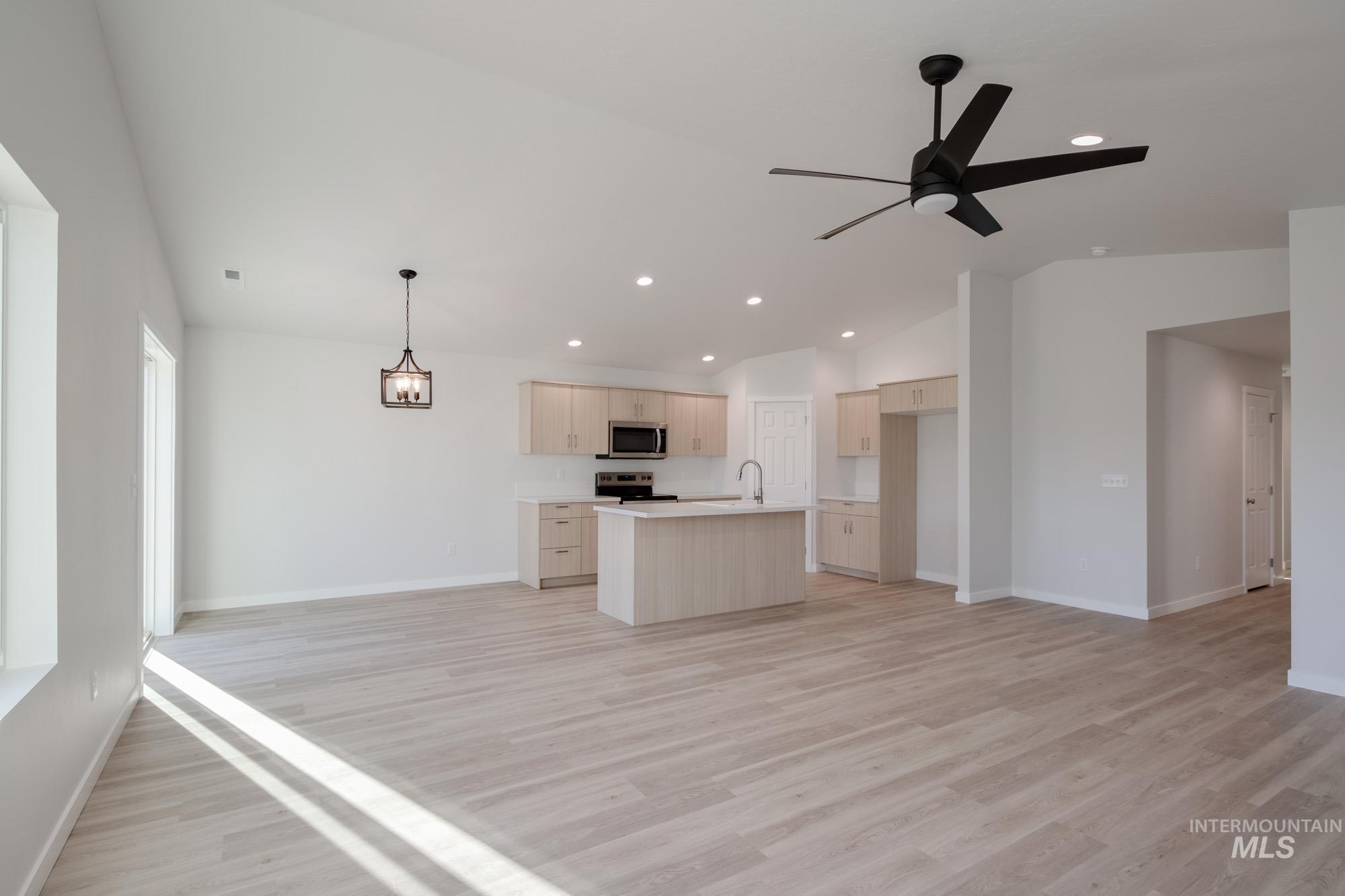 Kitchen featuring open floor plan, an island with sink, light countertops, lofted ceiling, and recessed lighting