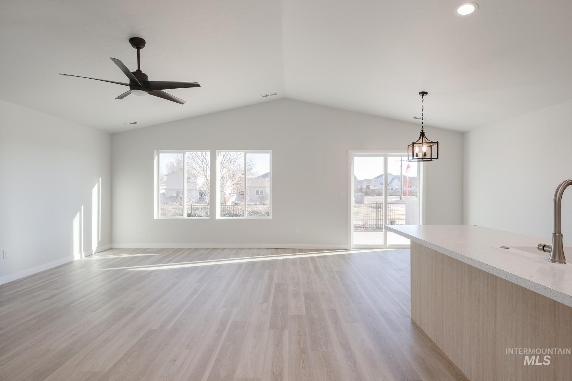 Unfurnished living room with light wood-type flooring, a ceiling fan, lofted ceiling, and recessed lighting