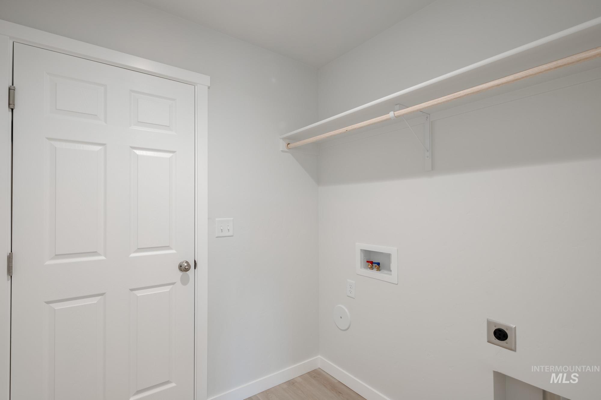 Laundry area featuring hookup for a washing machine, electric dryer hookup, and light wood-style flooring