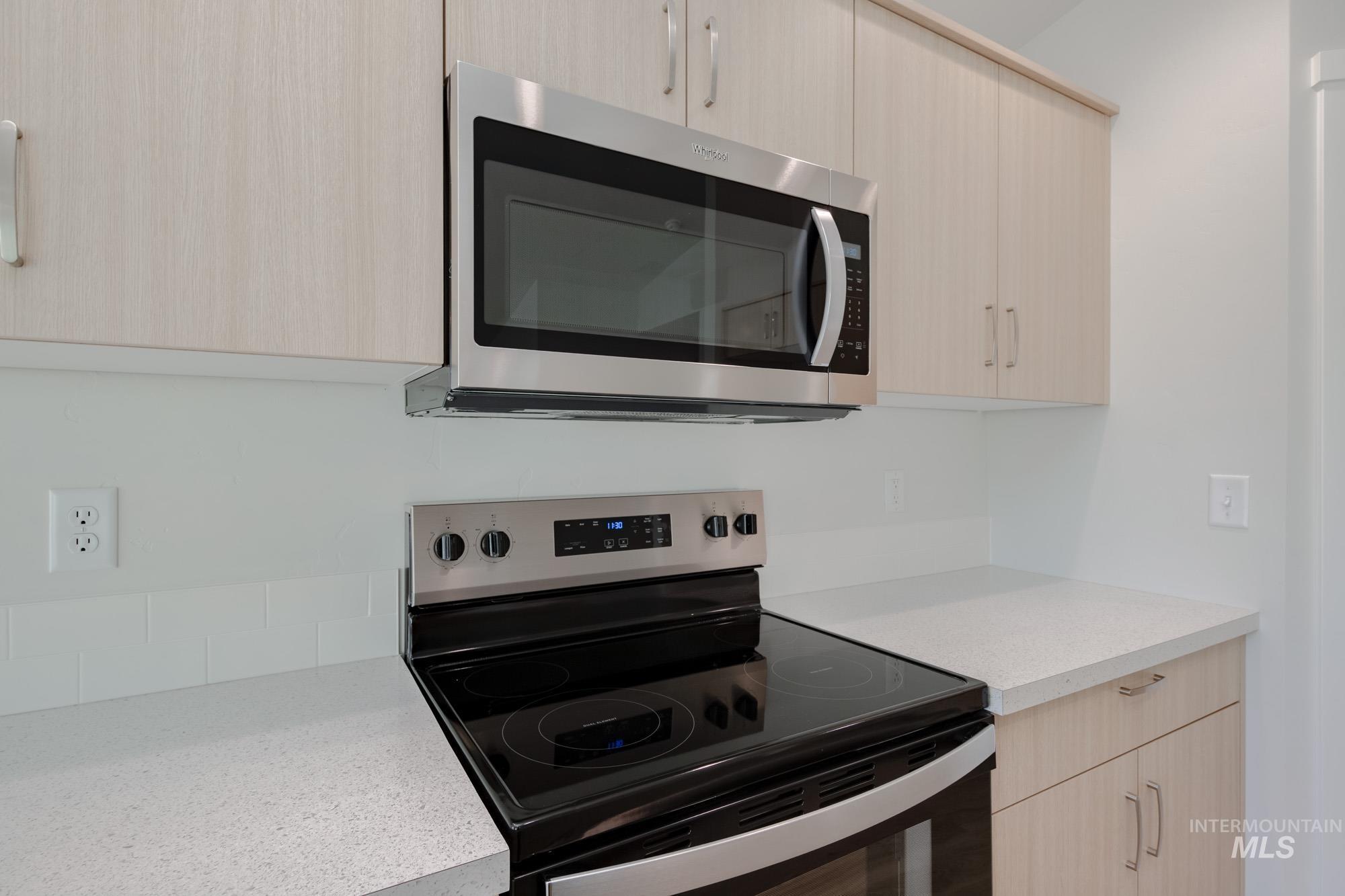 Kitchen with light brown cabinets, appliances with stainless steel finishes, and modern cabinets