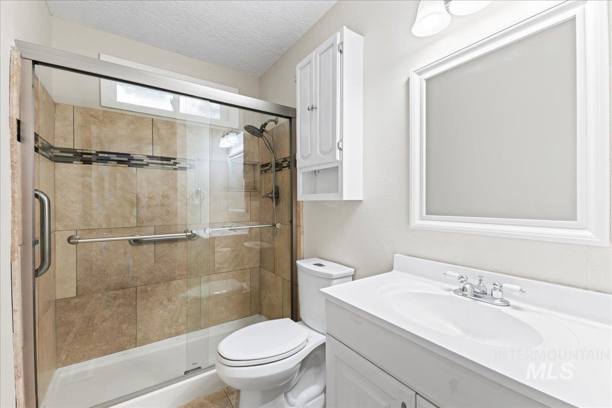Full bathroom with vanity, a textured ceiling, and a shower stall